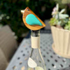 Bird-shaped bottle stopper on a wine bottle with a blurred outdoor background