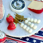 Assorted cheeses, strawberries, and a can of Coca-Cola on a marble surface with an American flag in the background.