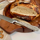 Loaf of bread with a serrated knife on a wooden cutting board