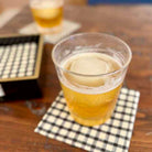 Clear plastic cup with beer on a checkered napkin on a wooden table