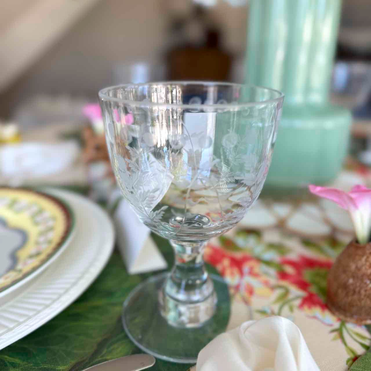 Clear glass goblet on a decorated table with plates and napkins.