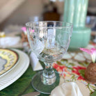 Clear glass goblet on a decorated table with plates and napkins.