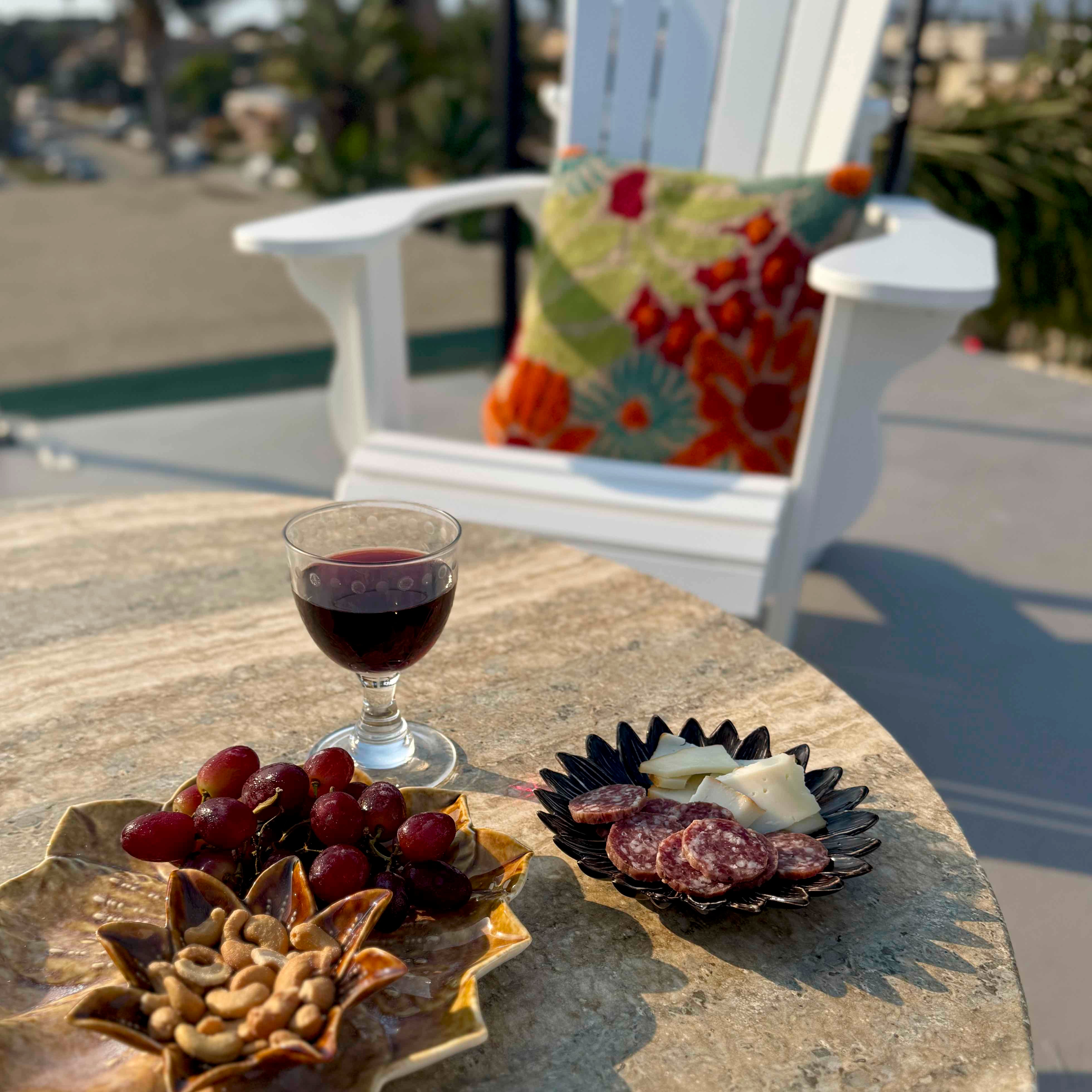 Glass of red wine with appetizers on a stone table outdoors.