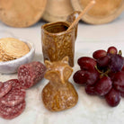 Ceramic fox-shaped container with snacks and fruits on a marble surface