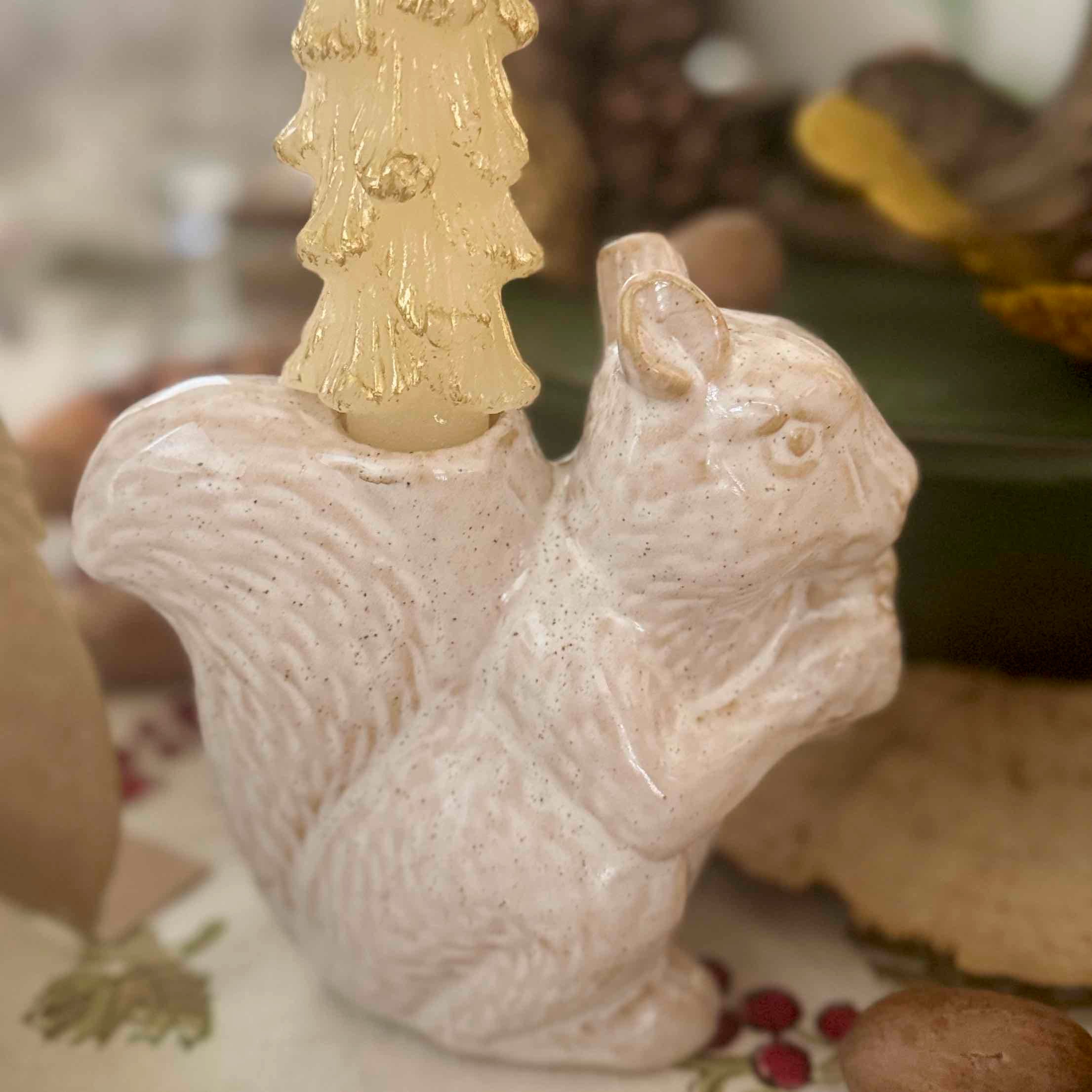 Decorative squirrel figurine with a gold candle on a blurred natural background
