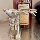 Silver deer head decanter stopper with a bottle of Evan Williams bourbon in the background.
