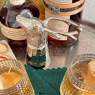 Bottle stopper with deer design in front of whiskey bottles on a table.