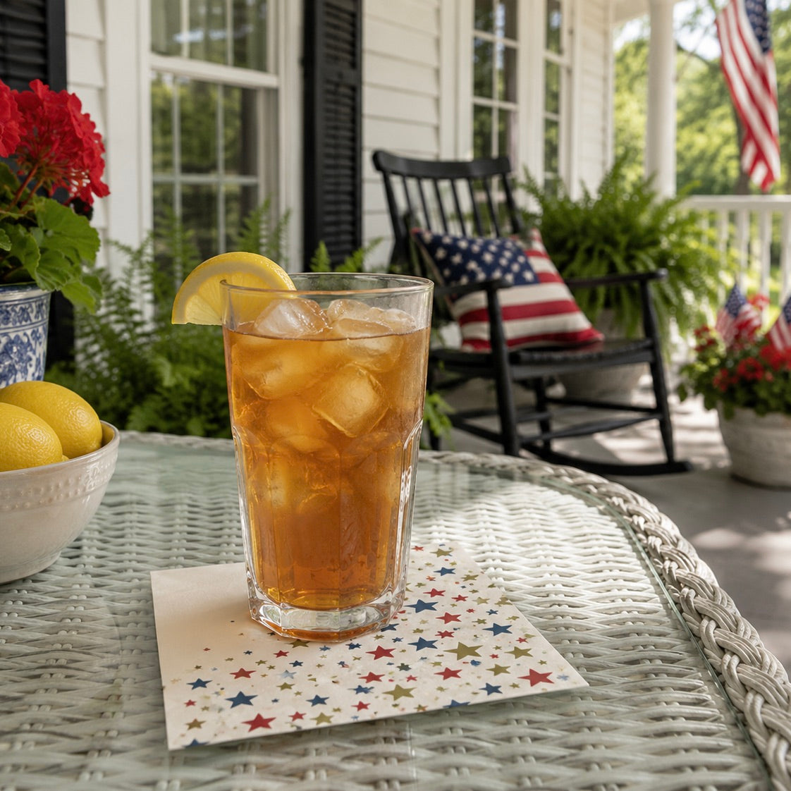 Glass of iced tea on a star-patterned napkin with a patriotic theme on a porch.