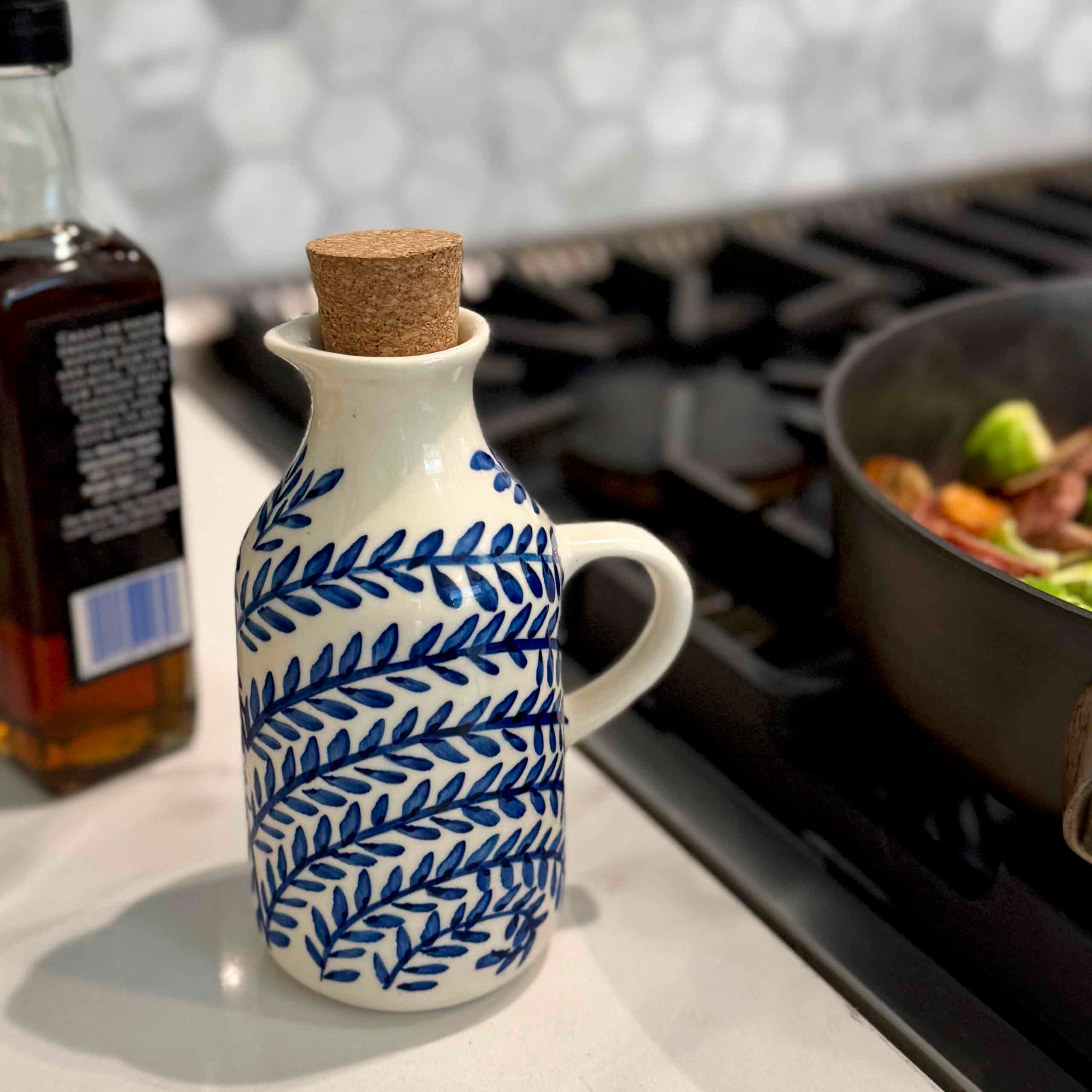 Ceramic bottle with blue leaf pattern on a kitchen counter