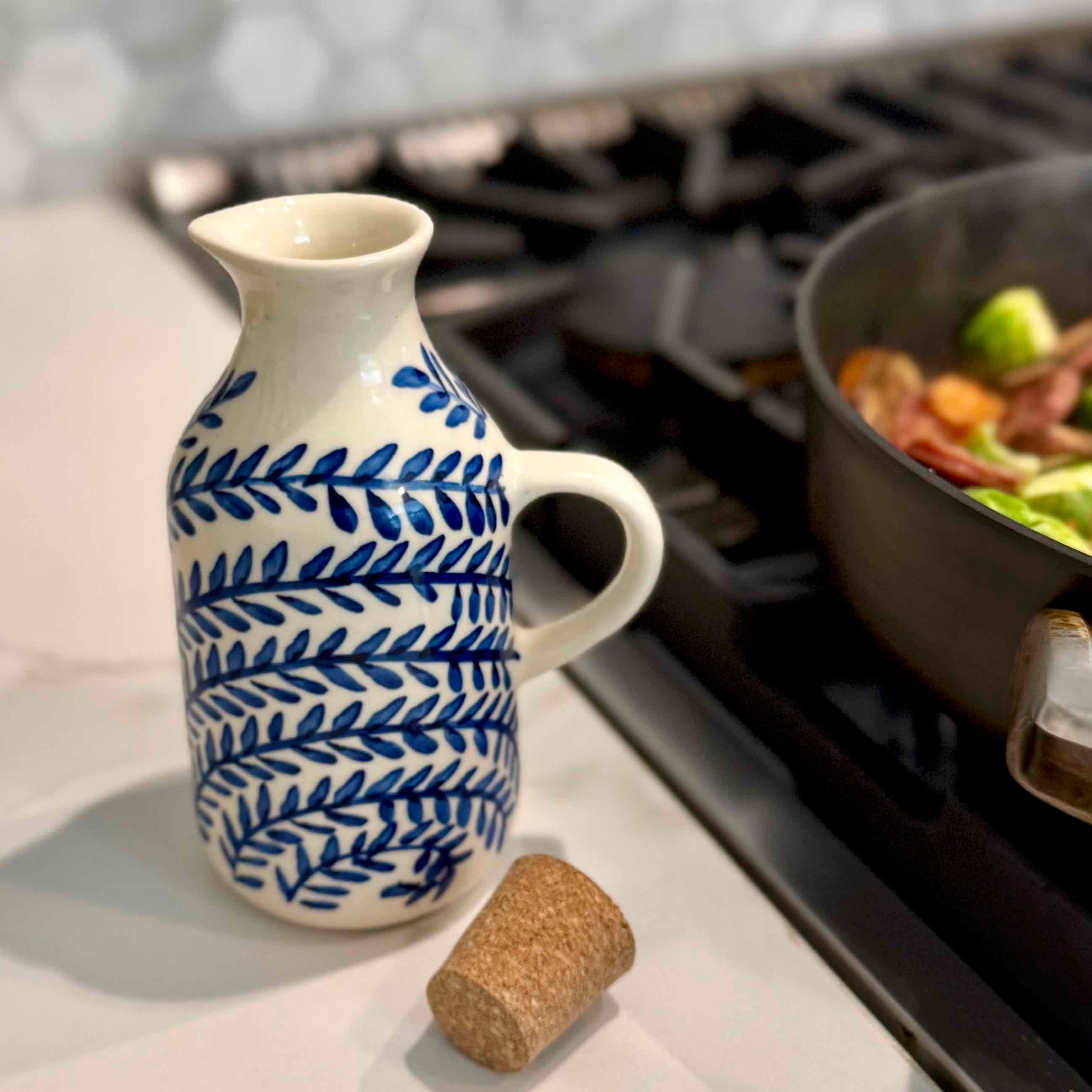 White ceramic pitcher with blue leaf pattern on a kitchen counter