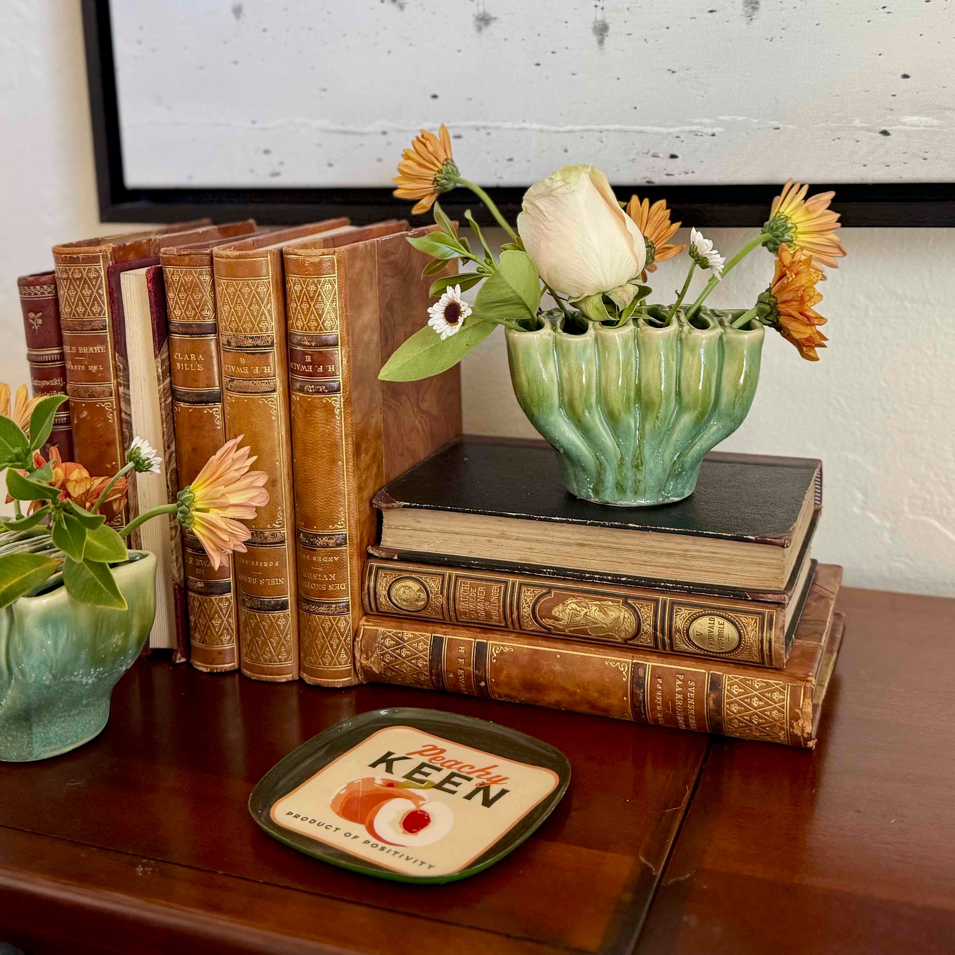 Stack of vintage books with a vase of flowers on a wooden surface