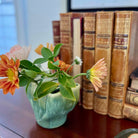 Vase with flowers on a surface next to vintage books