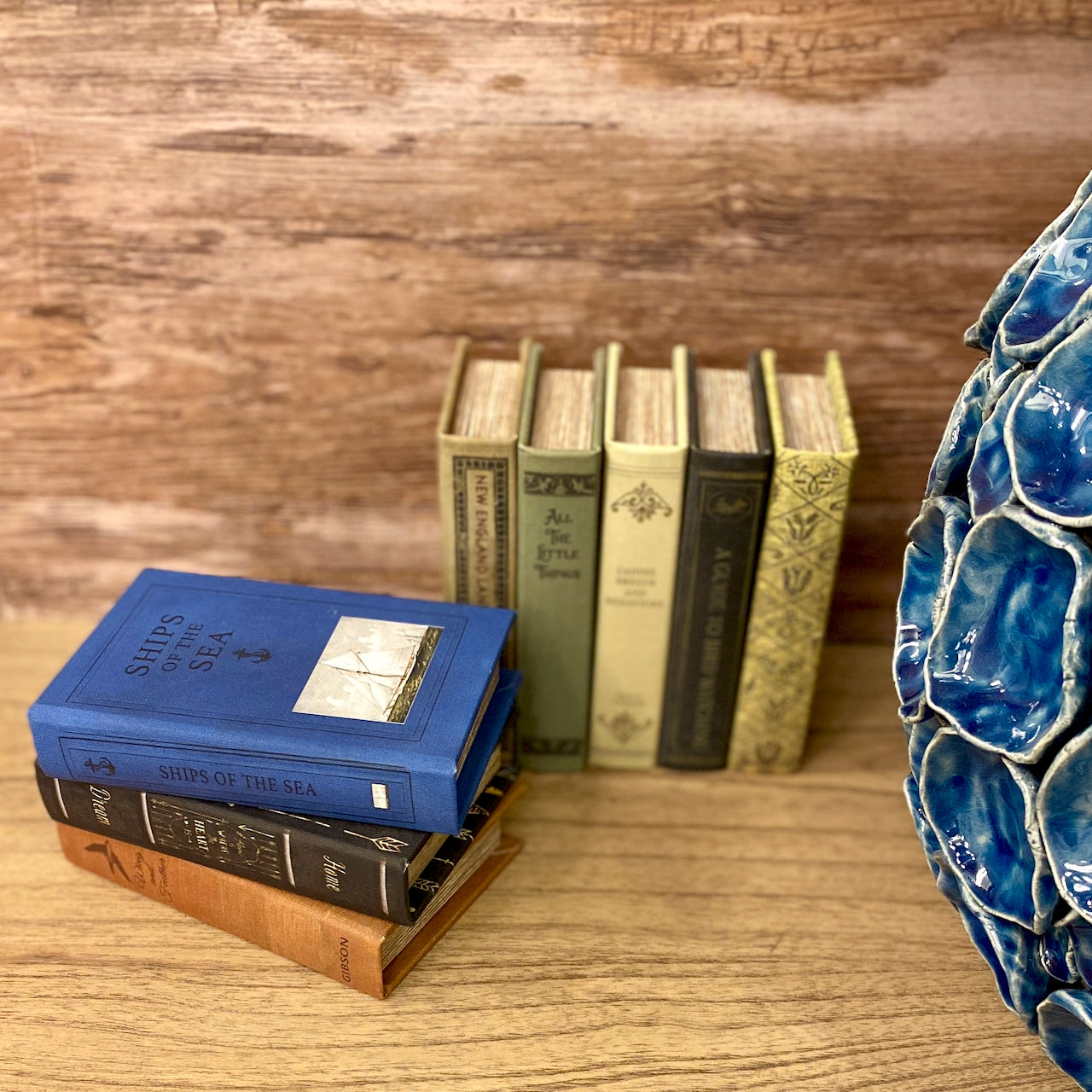 Stack of books with a blue decorative object on a wooden surface