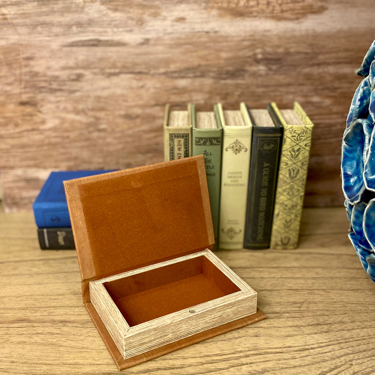 Wooden jewelry box on a wooden surface with books in the background