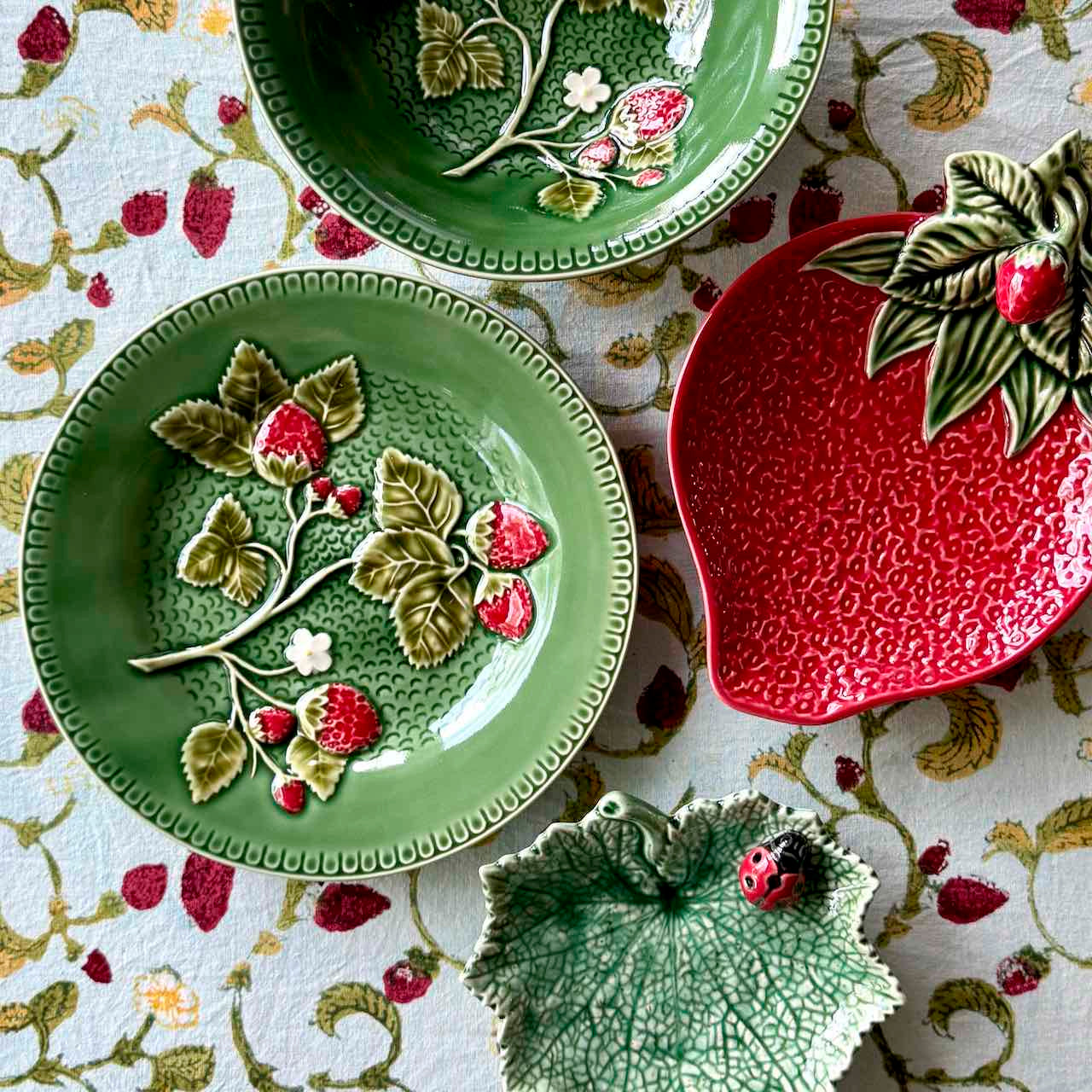 Set of ceramic plates with floral and leaf designs on a patterned fabric background