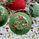 Decorative ceramic plates with floral and berry designs on a patterned tablecloth.