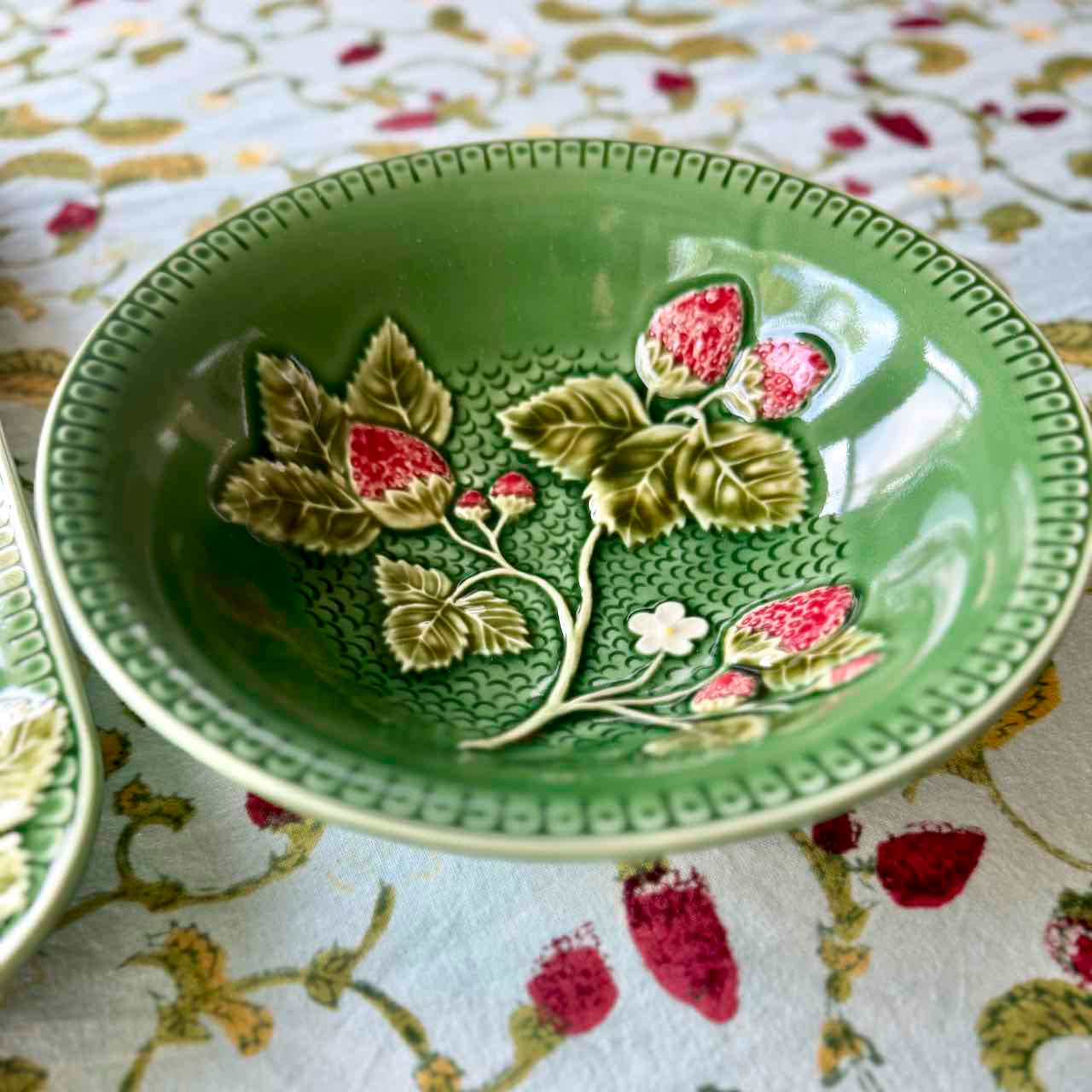 Green ceramic bowl with floral design on a patterned fabric background