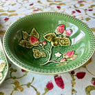 Green ceramic bowl with floral design on a patterned fabric background