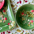 Green ceramic plates with floral designs on a patterned fabric background
