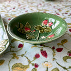 Green ceramic dish with floral design on a patterned tablecloth