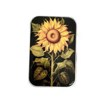 A rectangular tin with rounded corners featuring a vintage-style illustration of a sunflower on a black background, shown against a plain white studio background.