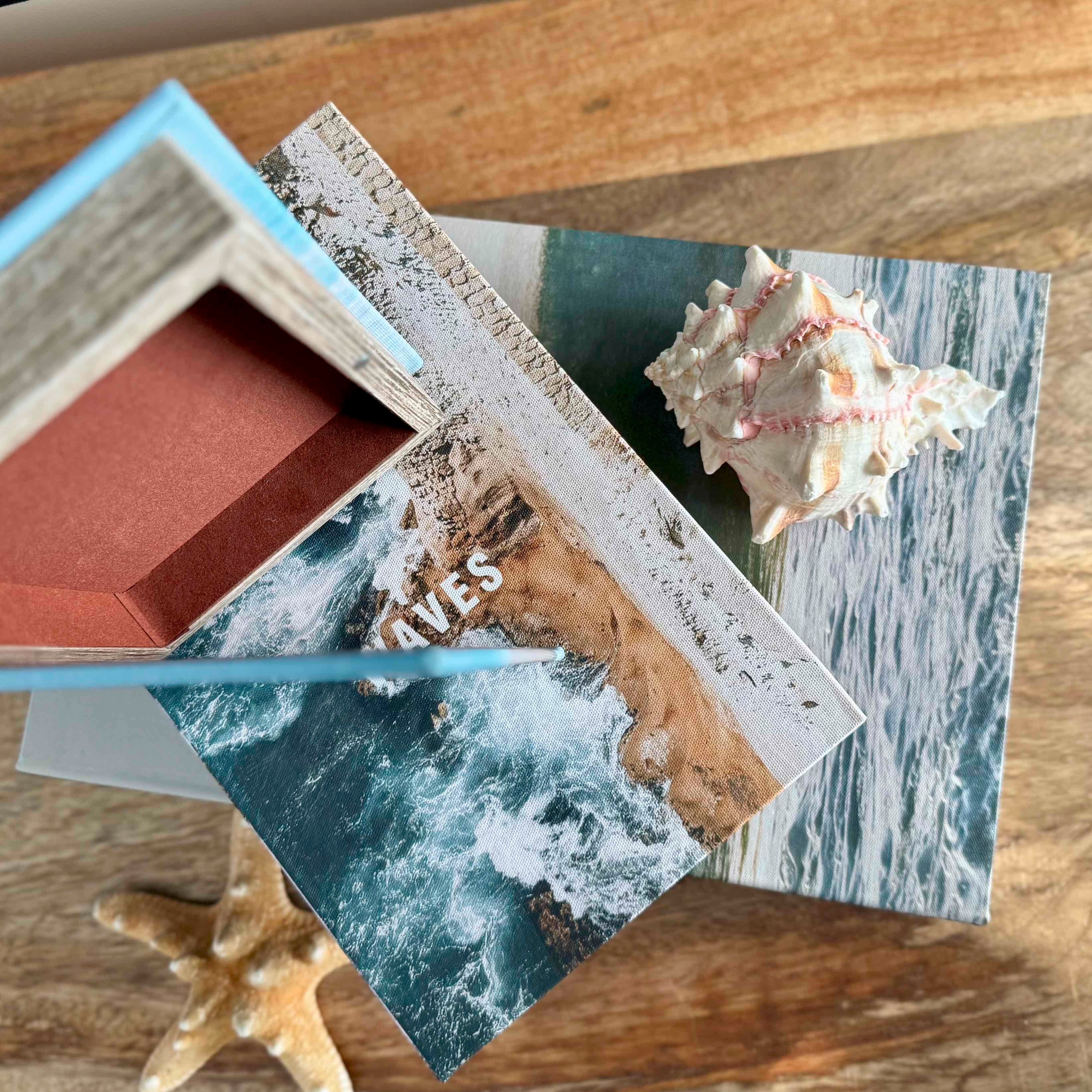 Stack of photo albums with a shell and starfish on a wooden surface