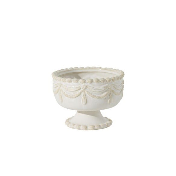 An off-white ceramic pedestal bowl with embossed classical drapery and beaded detailing on the rim, set against a plain white background.