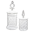 Two clear glass jars with decorative lids on a white background