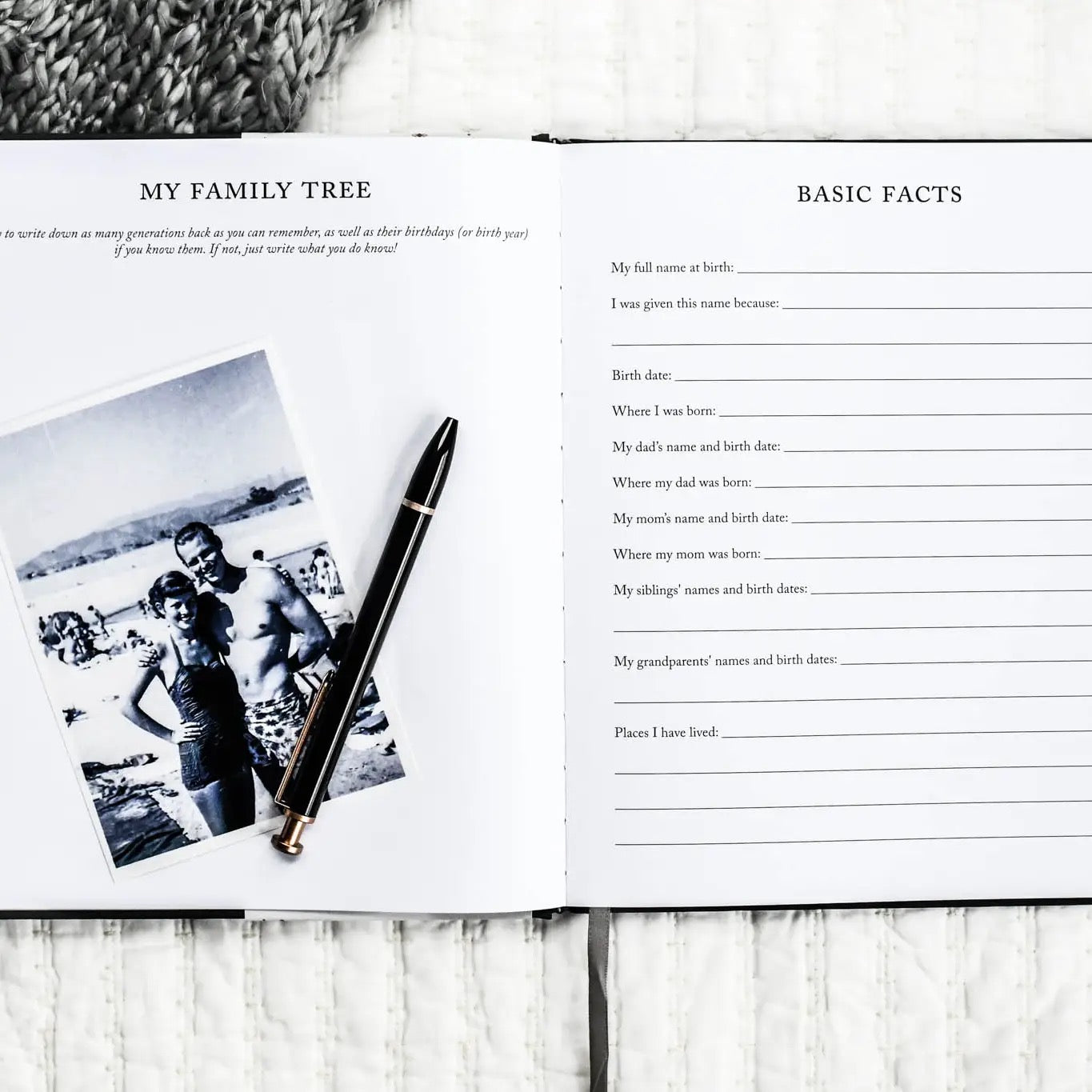 Open book with family tree and basic facts questionnaire on a wooden surface with a pen and photo.