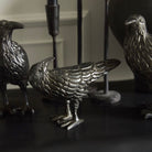 Three metallic bird figurines on a dark surface with a blurred background