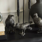 Decorative metal bird figurines on a dark surface with a neutral background