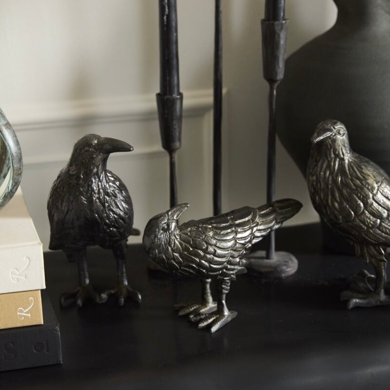 Decorative metal bird figurines on a dark surface with a neutral background