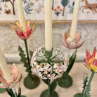 Decorative candle holder with floral design against a patterned wall