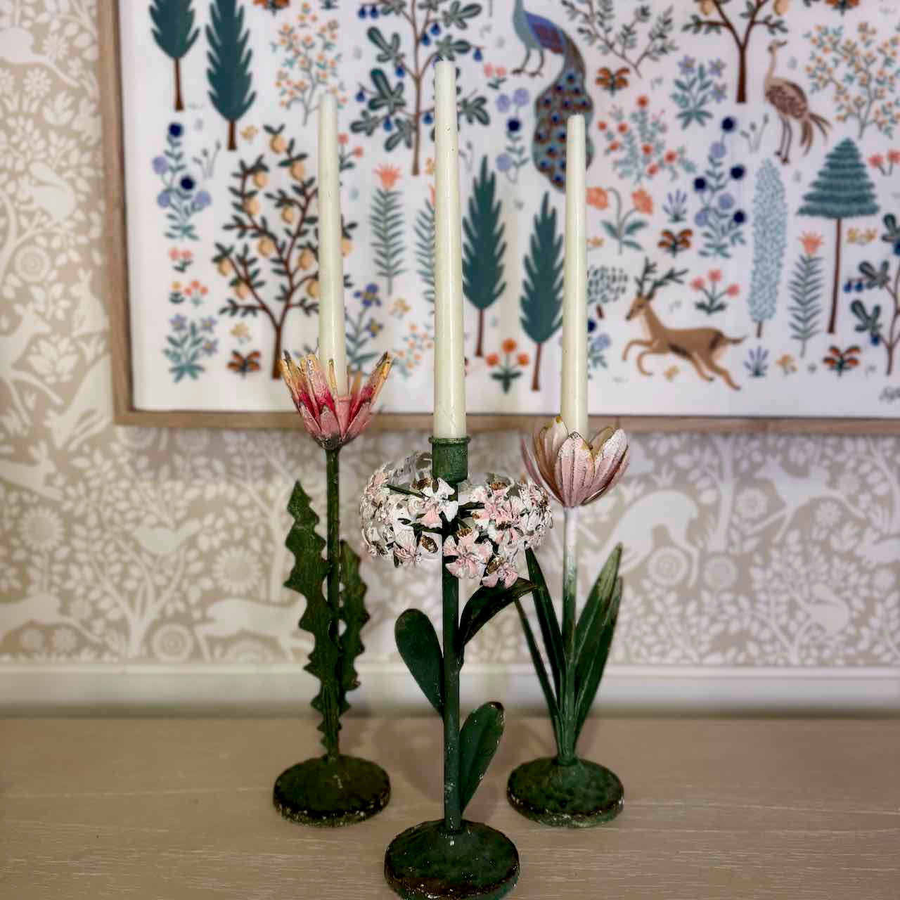 Decorative candle holders with floral designs against a patterned wall.
