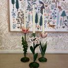 Decorative candle holders with floral designs against a patterned wall.