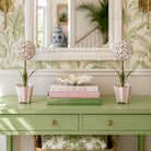 Decorative setup with books, vases, and a mirror on a green surface.