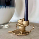 Brass mouse-shaped candle holder with a candle on a neutral background