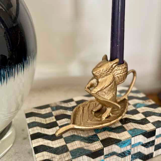 Brass mermaid candle holder on a decorative box with a blurred background