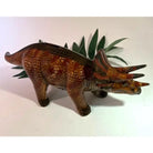 Dinosaur toy figure on a white background with green leaves