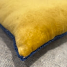 Close-up of a yellow pillow with blue trim on a textured surface