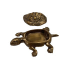Bronze turtle-shaped container with a smaller stone on a white background