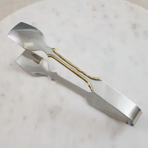 Metallic tongs on a marble surface