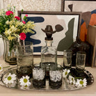 Decorative tray with glassware, flowers, and a cowboy-themed bottle on a table.