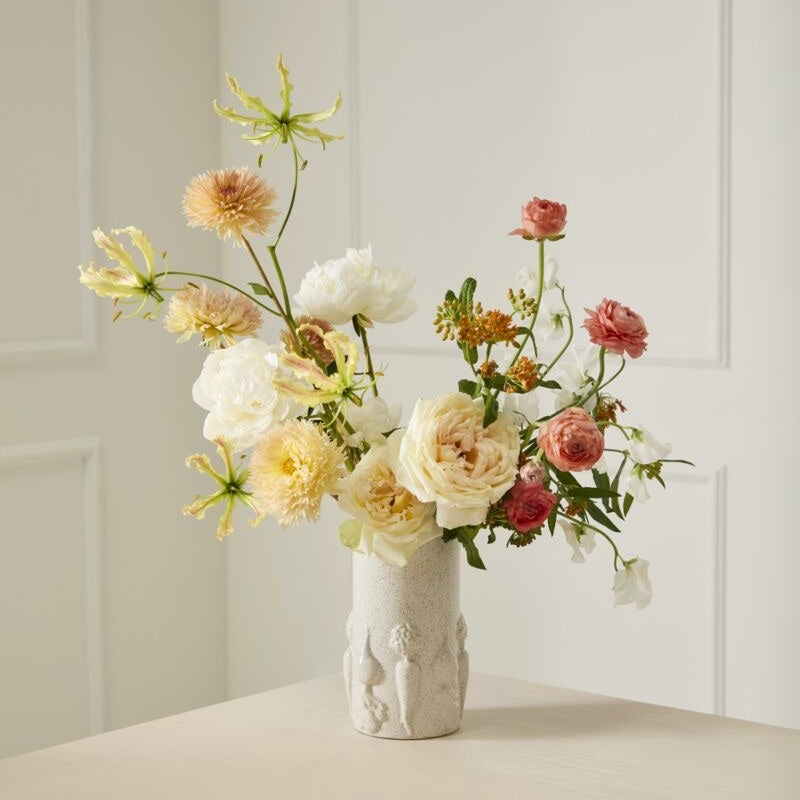 Floral arrangement in a textured vase on a neutral background