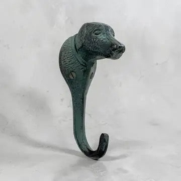A decorative hanging hook shaped like a dog's head, finished with a dark green patina and blackened highlights, set against a light gray textured background.