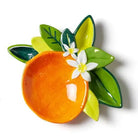 Decorative ceramic orange with green leaves and a white flower on a white background