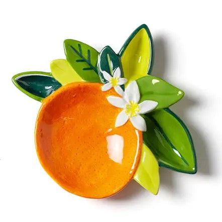 Decorative ceramic orange with green leaves and a white flower on a white background