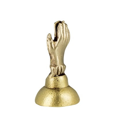 A small metallic gold figurine depicting praying hands on a round pedestal base, isolated on a white background.