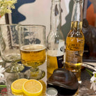 Two Corona beer bottles with a glass of beer and lemon slices on a table.