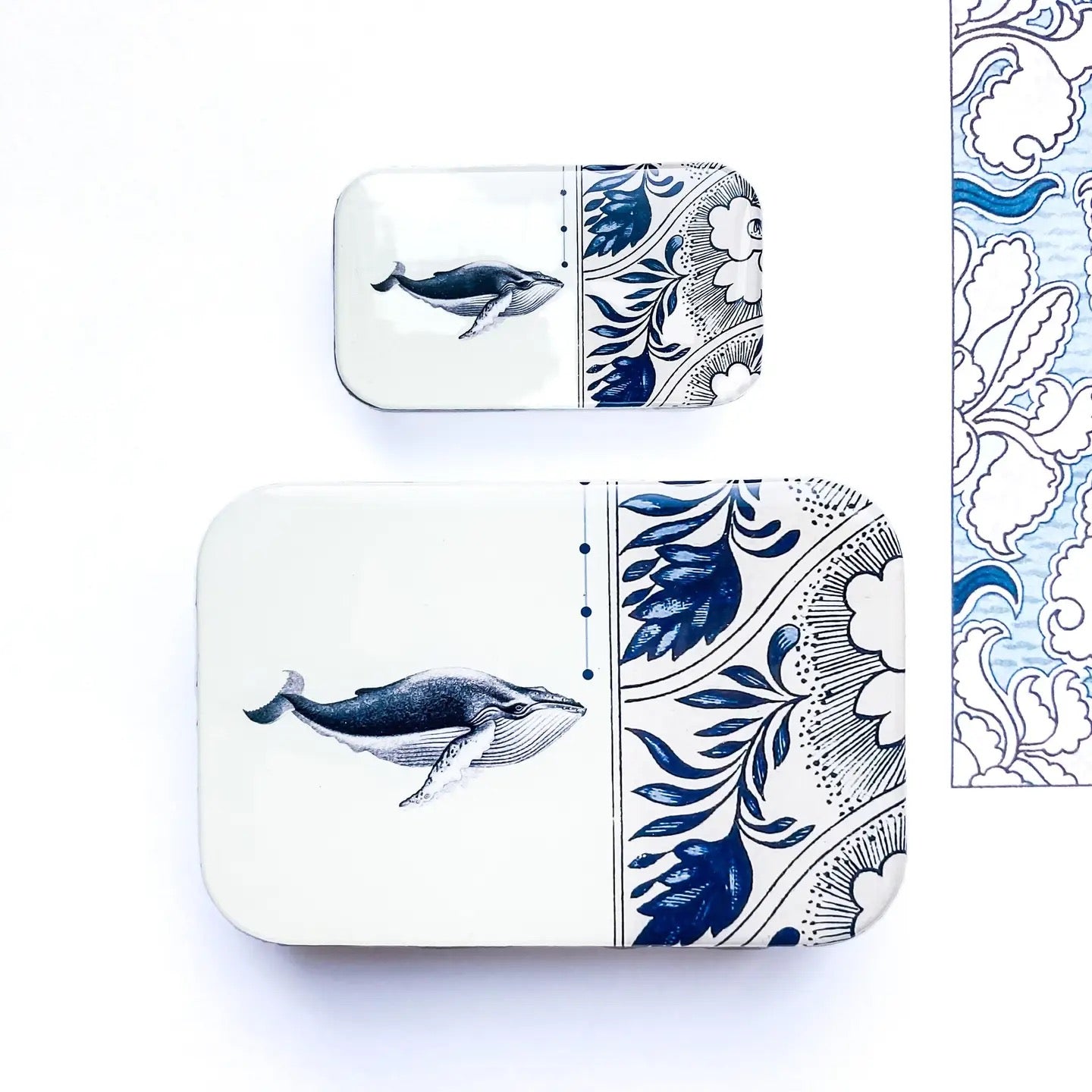 Two square containers with whale and floral designs on a white background